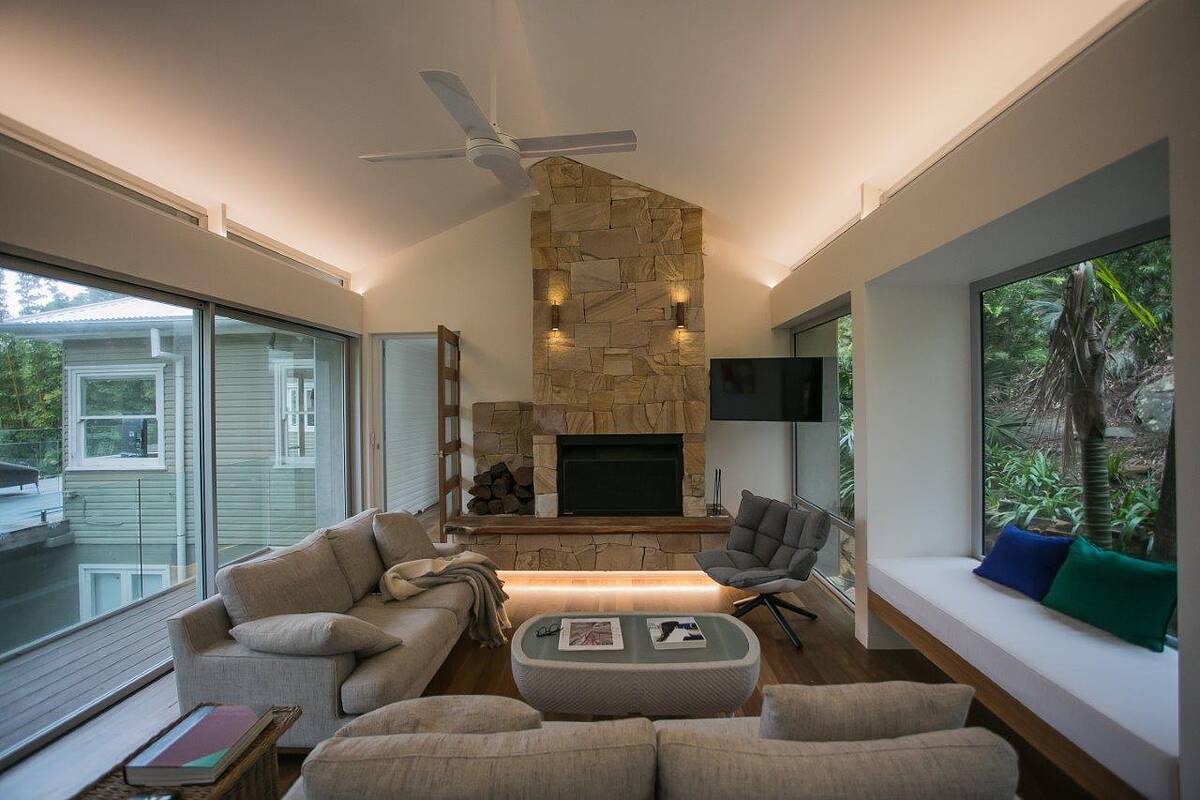 Floor-to-ceiling sandstone fireplace and chimney breast under a raked ceiling in a Bilgola Beach living room
