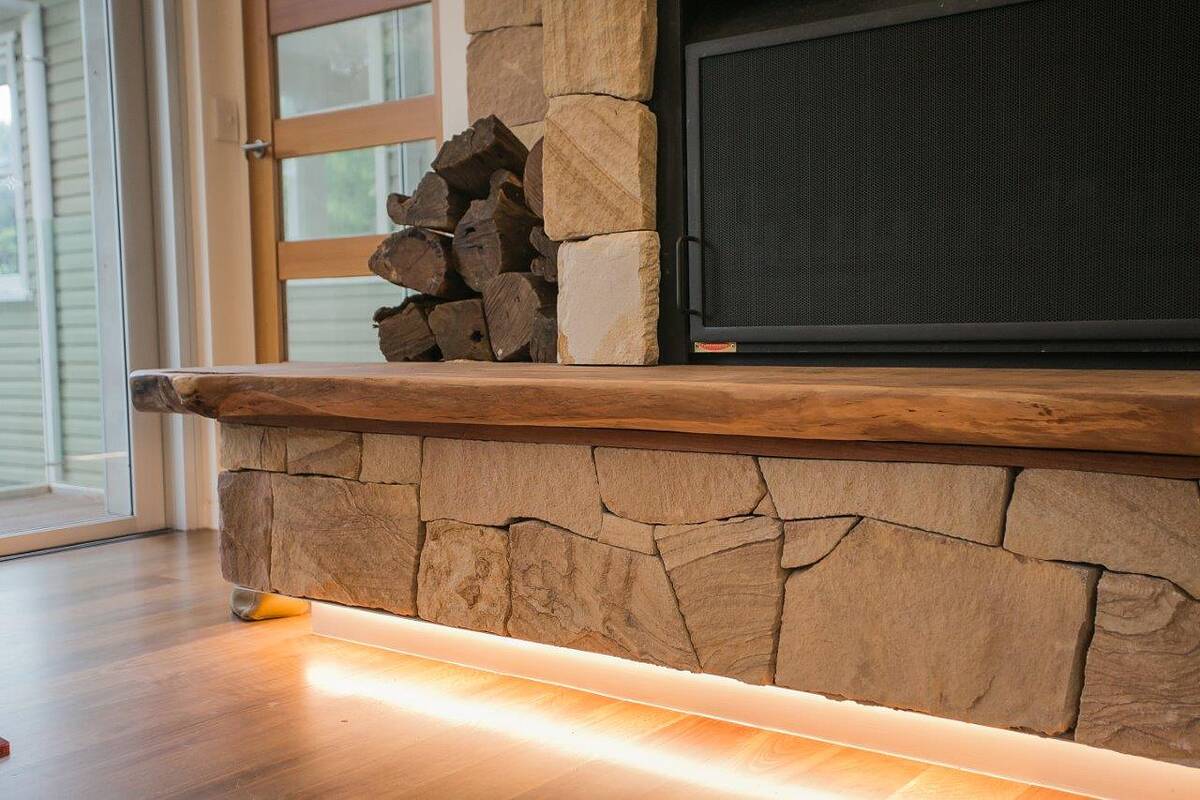 Sandstone hearth with LED under-lighting, recycled timber mantel and stacked firewood