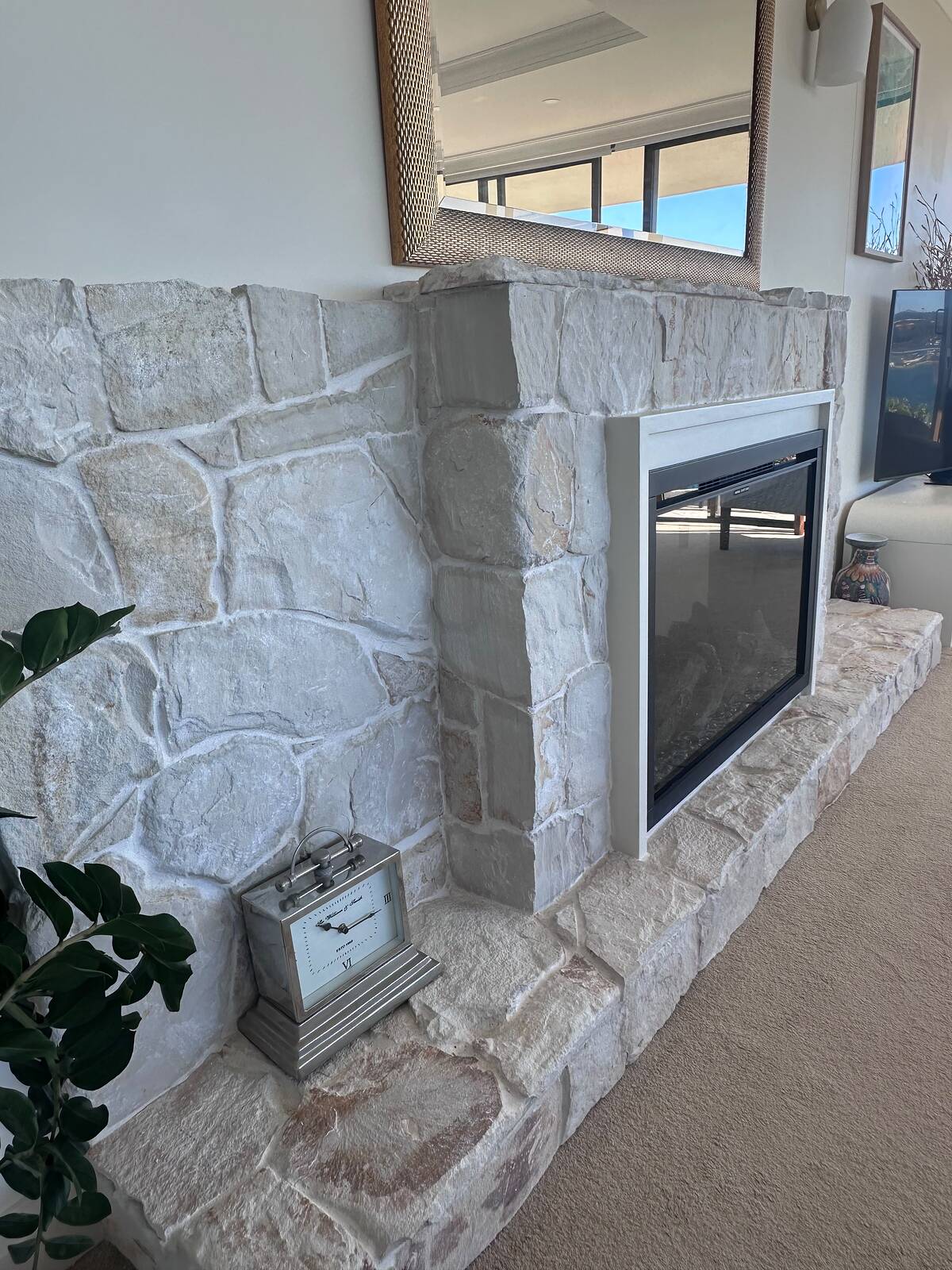 Close-up of light random natural stone fireplace cladding and raised block hearth