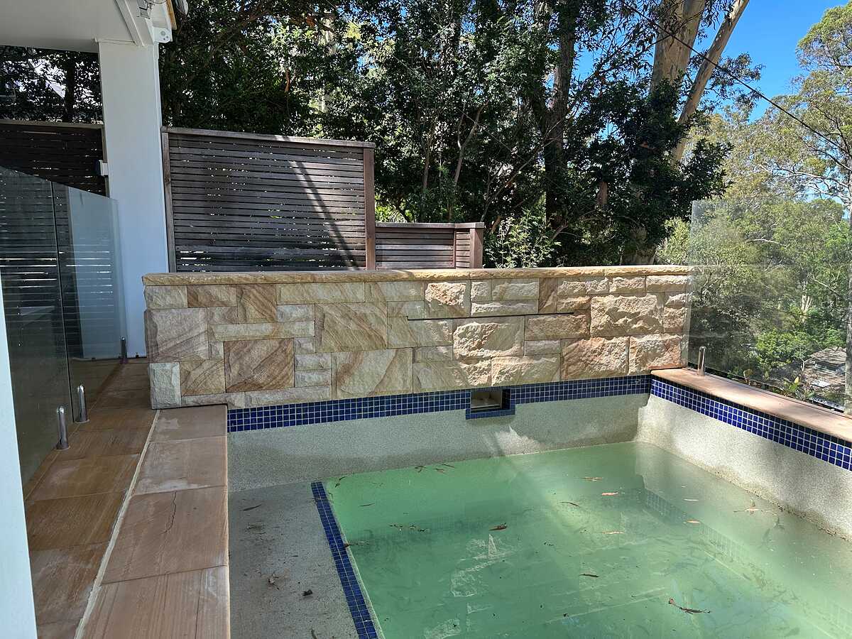 Plunge pool with split-face sandstone feature wall, sandstone coping and paving