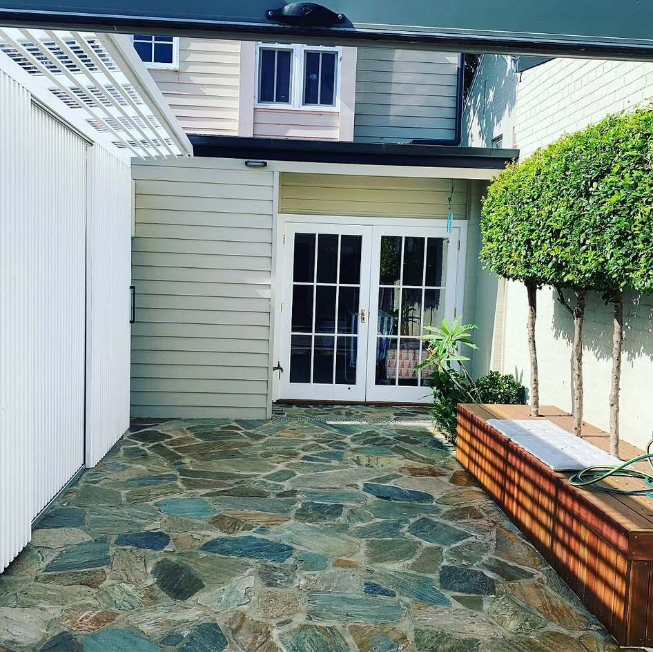 Green-blue crazy paving in a terrace courtyard leading to white French doors