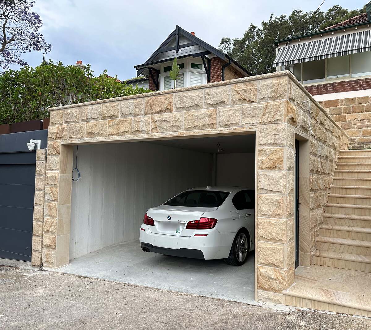 Rock-face sandstone clad garage with sawn sandstone staircase in front of a Federation home
