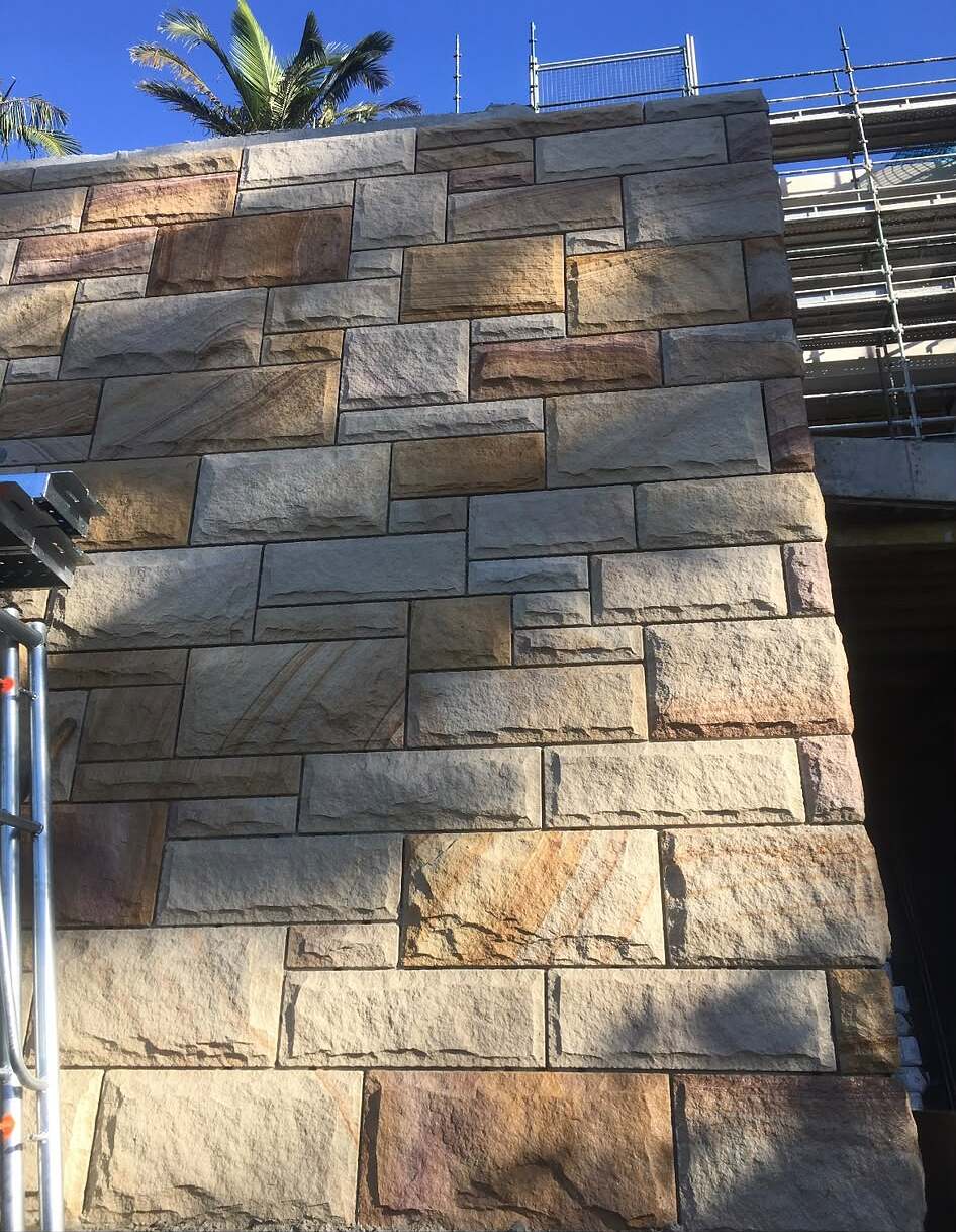 Multi-toned sandstone ashlar cladding on an exterior wall under construction