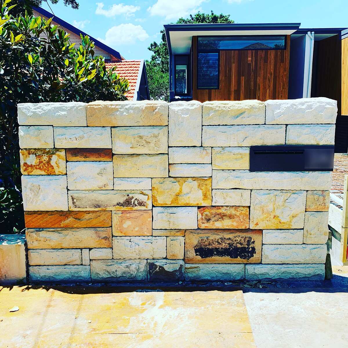 Sandstone ashlar front wall with a built-in black letterbox