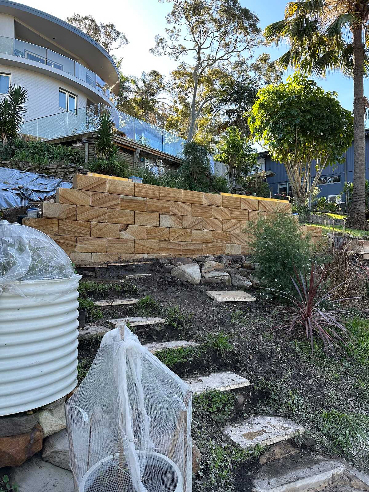 Sandstone block retaining wall and stepping-stone path on a steep hillside garden