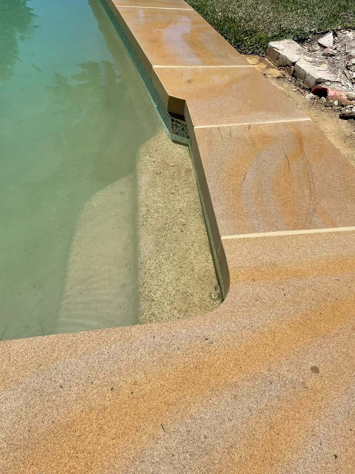 Close-up of bullnose sandstone pool coping around a pool step