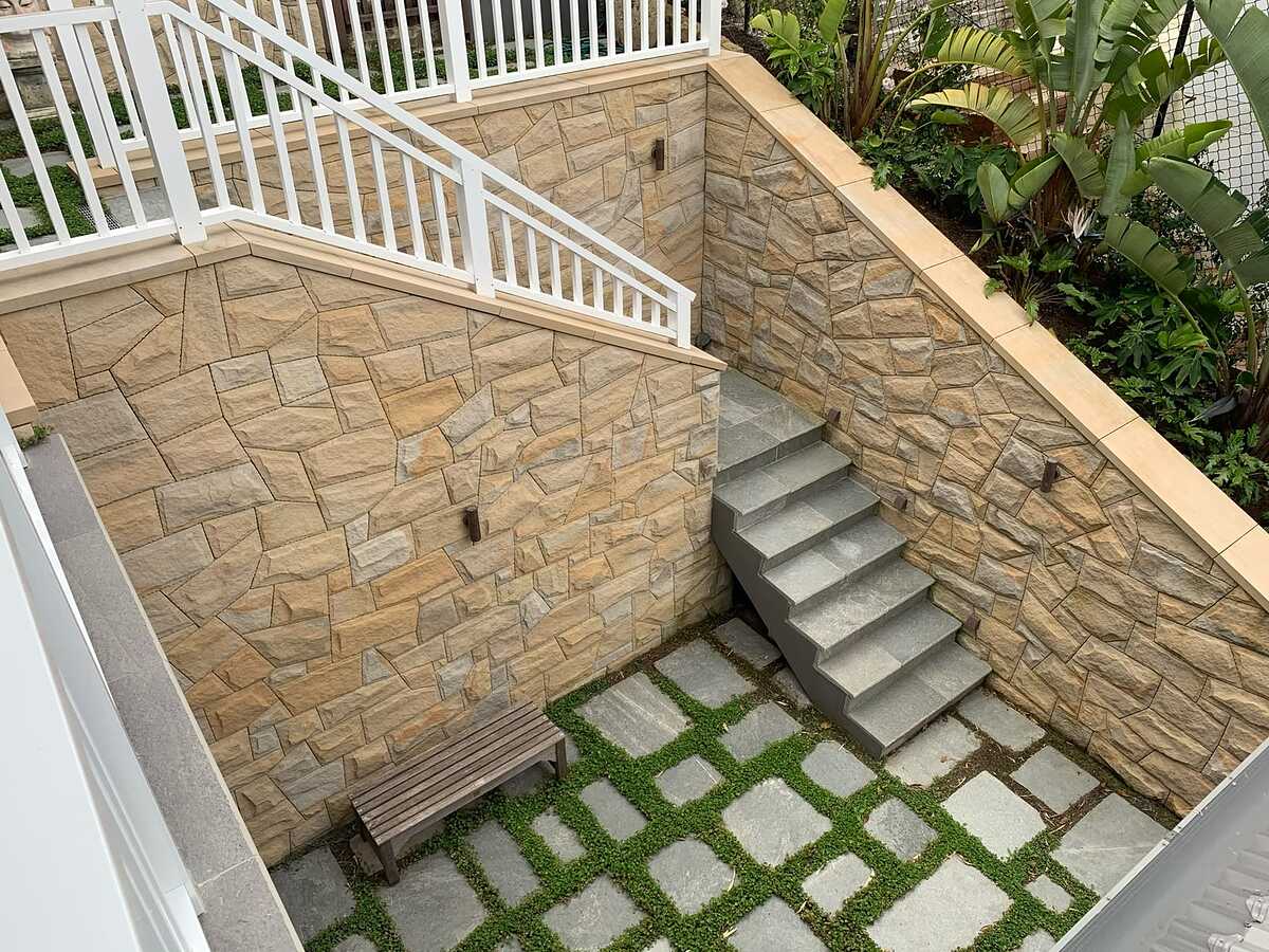 Sunken courtyard with sandstone-clad walls, bluestone stairs and stepping pavers