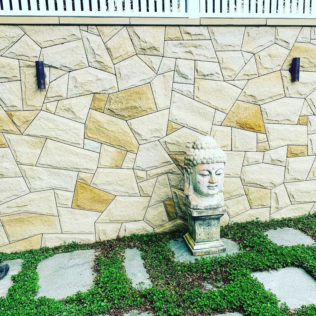 Sandstone-clad garden wall with stepping stones set in groundcover
