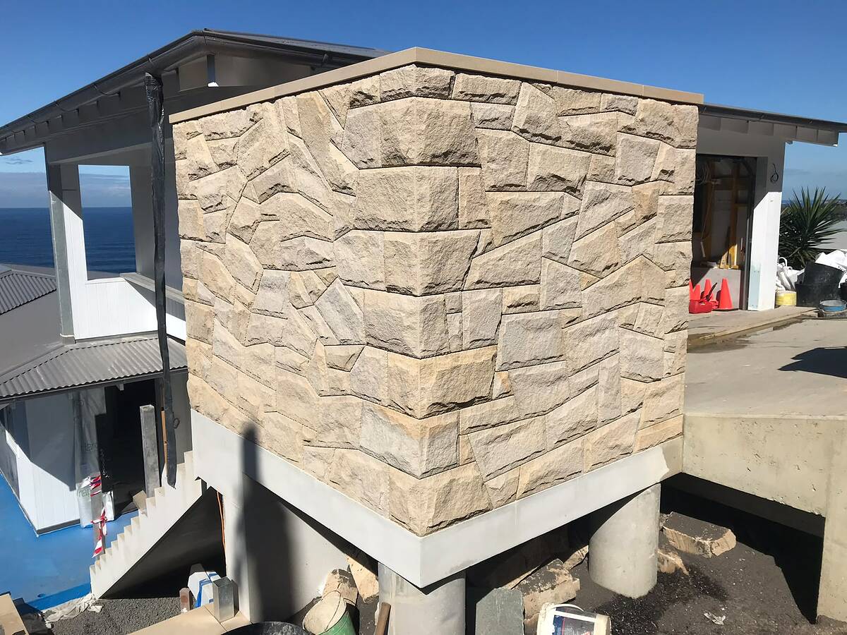 Light sandstone cladding on a new coastal home under construction with ocean views