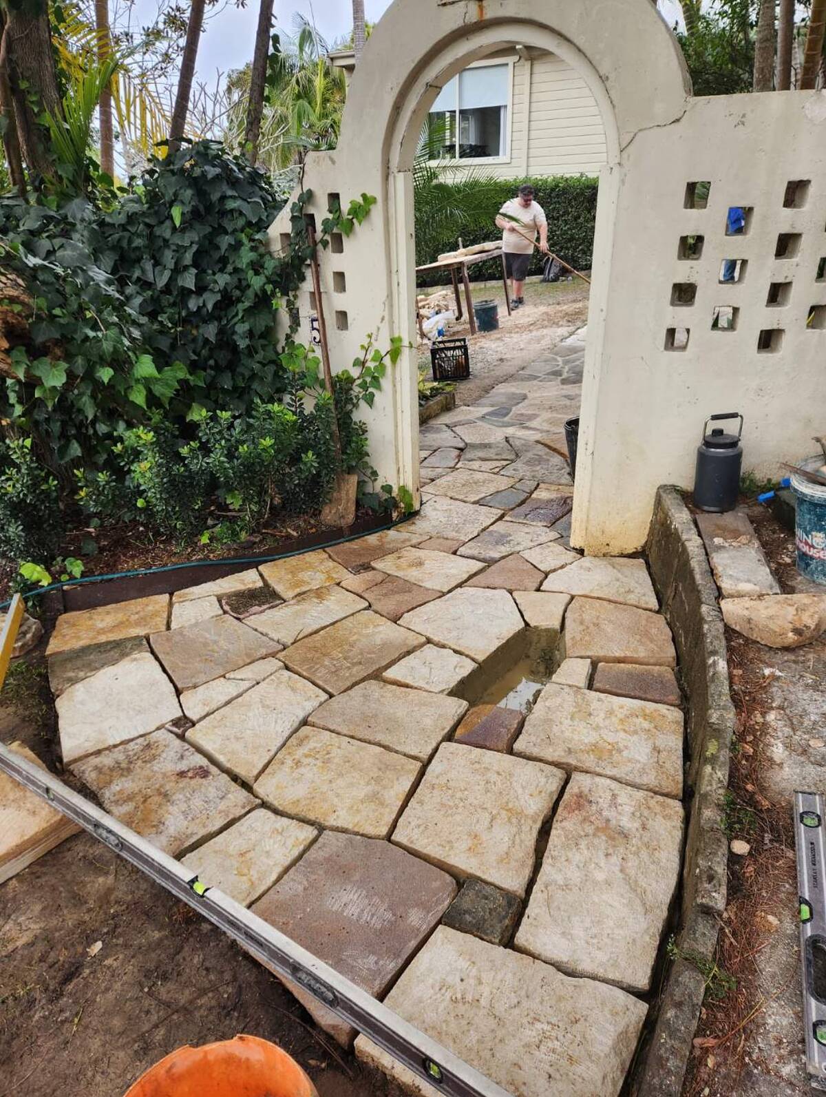 Sandstone crazy paving path curving through a rendered garden arch