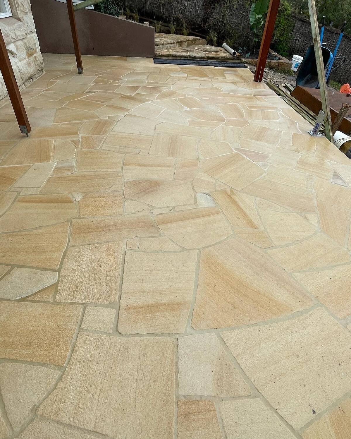 Sandstone crazy paving patio under a timber pergola frame