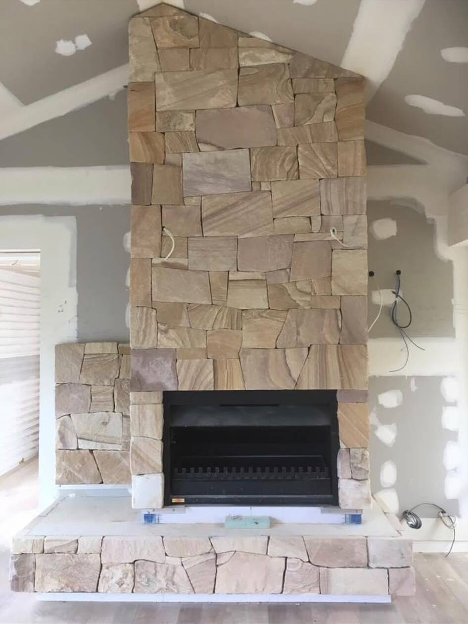 Sandstone fireplace chimney breast and hearth in a renovation with a raked ceiling