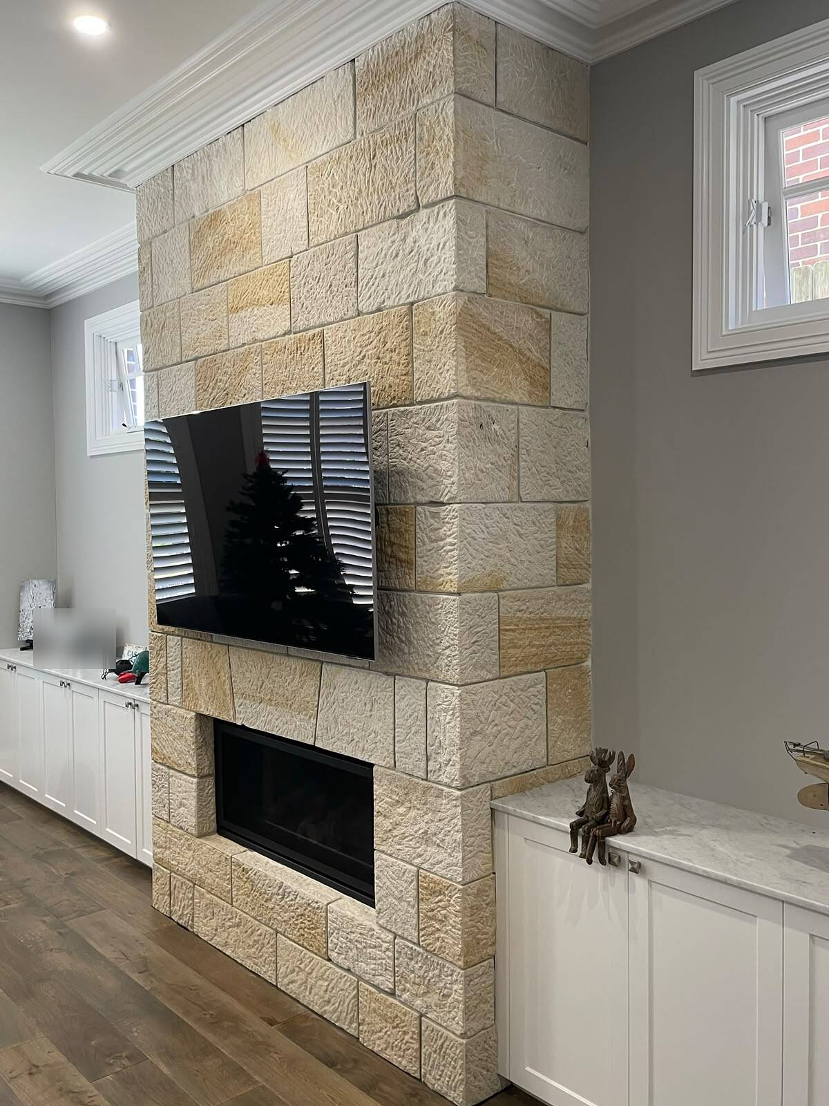 Floor-to-ceiling sandstone fireplace with wall-mounted TV and linear gas fire