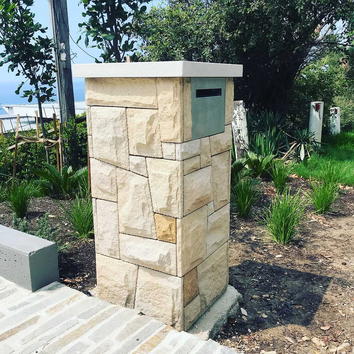Light sandstone letterbox pillar with smooth capping in a coastal garden