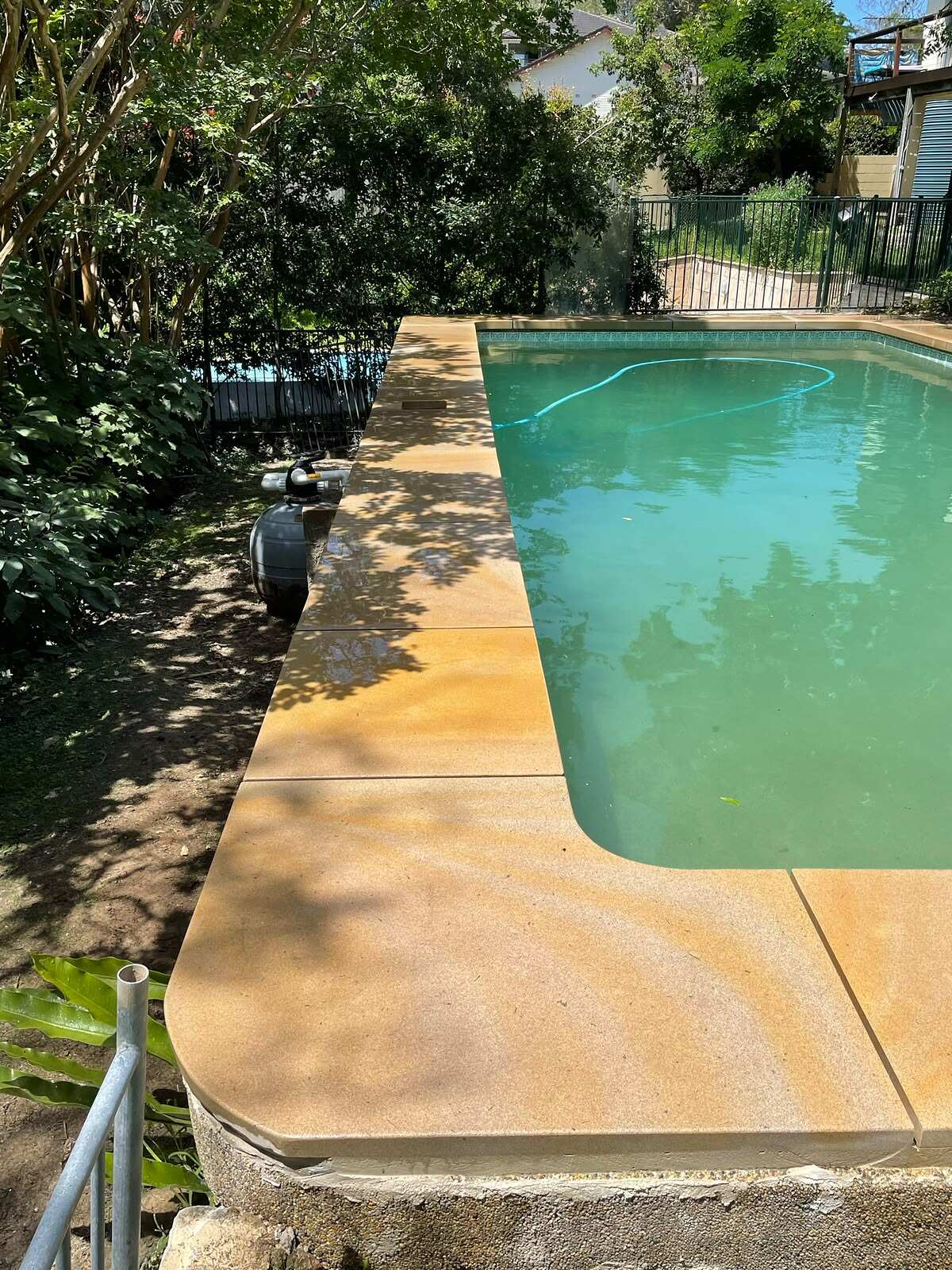 Wide sawn sandstone pool coping with rounded corners around a backyard swimming pool