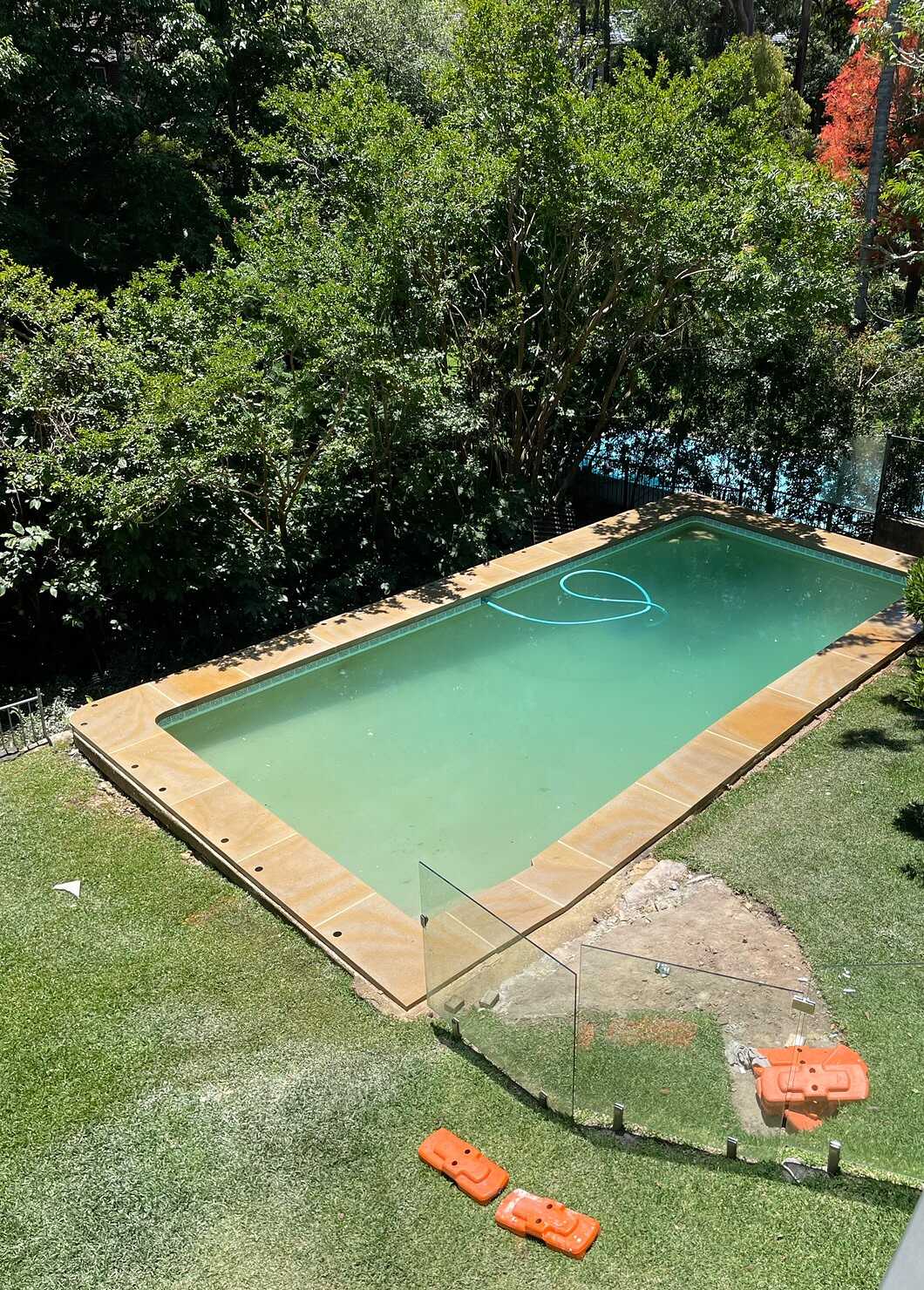 Sandstone pool coping around an in-ground pool in a leafy garden
