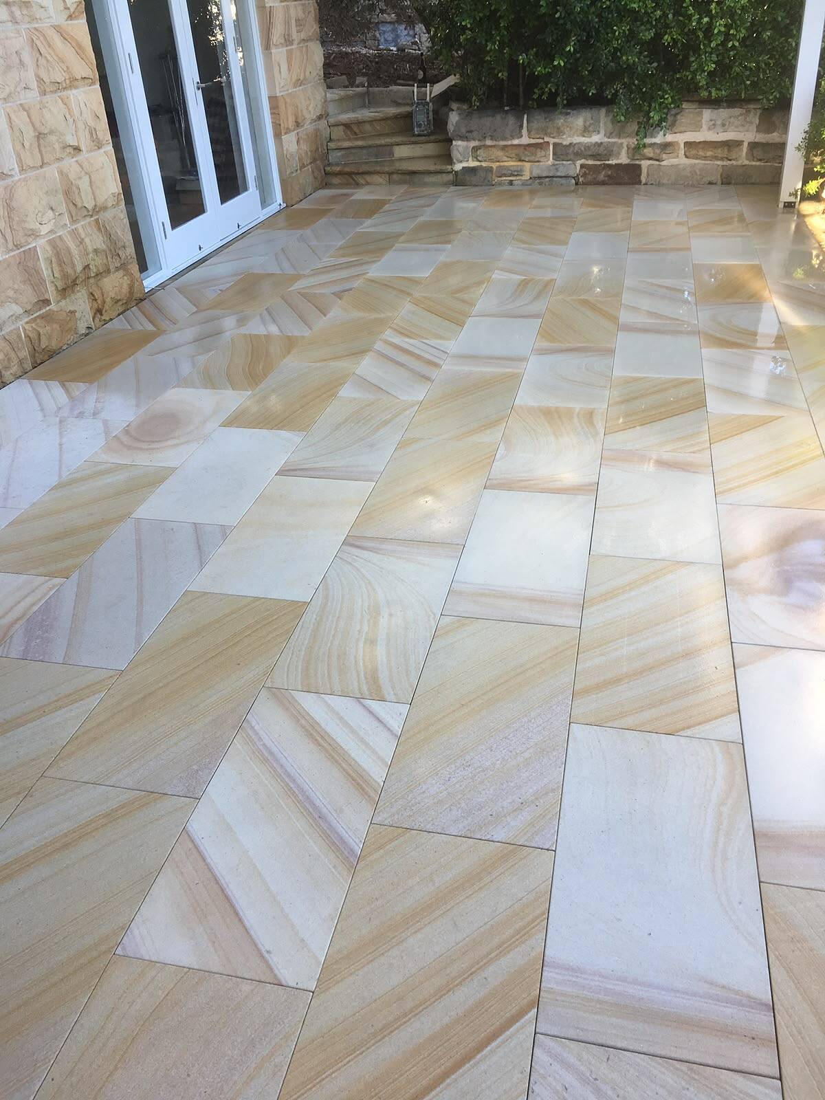 Banded sawn sandstone pavers on a patio outside French doors
