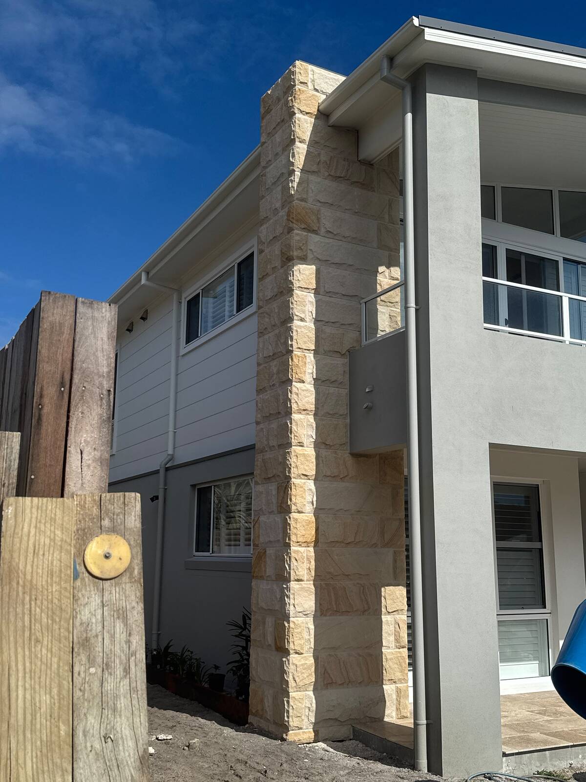Full-height split-face sandstone cladding on a pillar of a modern two-storey house