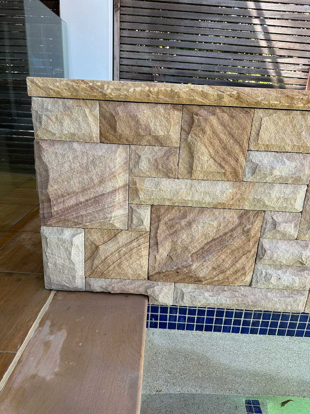 Corner detail of split-face sandstone pool wall and sawn sandstone coping