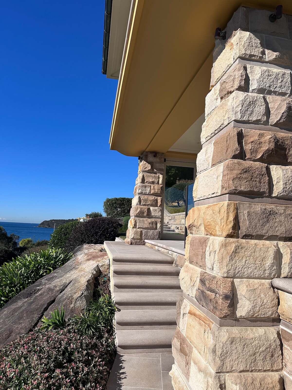 Sandstone clad columns and sawn steps at a waterfront home overlooking the ocean